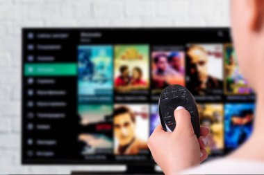 Multimedya yayın konsepti. Uzaktan kumandalı kadın eli. Bir sürü resimli TV ekranı.