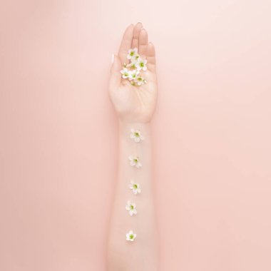 Yazın moda sanatçısı kadın ve elinde çiçekler. Yaratıcı fotoğrafçı kızlar pembe arka planda masada oturuyorlar. Cilt bakımı konsepti