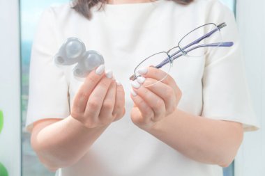 Kadın bir elinde gözlük, diğer elinde kontakt lens tutuyor. Miyop ve görme bozukluğu, görme sorunu
