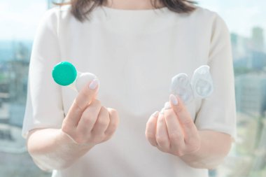 Bir kadın yeniden kullanılabilir lensleri bir elinde tutarken bir gün kontakt lensler diğer elinde. Görme sorunu kavramı