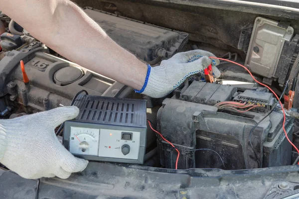 Close-up of male hands checking voltage of automobile battery under hood machine with accuracy. Automotive checkup concept. lifestyle.