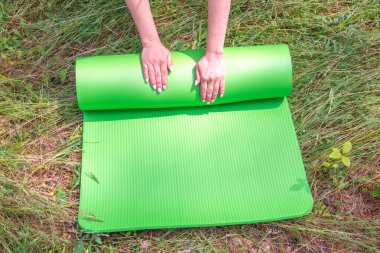 Kadın ellerine yakın çekim, doğada rahatlamak için yoga minderi tutar. Sağlıklı yaşam tarzı kavramı