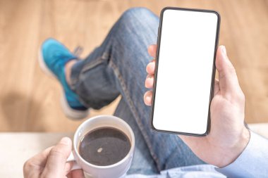 Model cep telefonu. Erkeklerin cep telefonlarının uyluk ve kahve fincanlarında boş ekran görüntüsü..