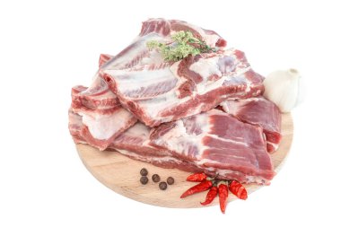 Çiğ domuz kaburgası ve baharatlar ahşap bir kesme tahtasına serilmiş. Ahşap arka planda baharatlı çiğ domuz pirzolası. Çiğ domuz kaburgası, biber, fesleğen ve sos.