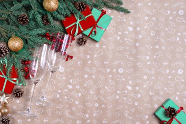 Sanat eserlerinin arka planında Noel dekoru. Noel ağacı dalları, kırmızı kurdeleli hediye kutuları, kırmızı süslemeler, ışıltılar ve şampanya bardakları. Noel ve yeni yıl tebrik kartı, kış tatili. Düz yatış, üst görünüm