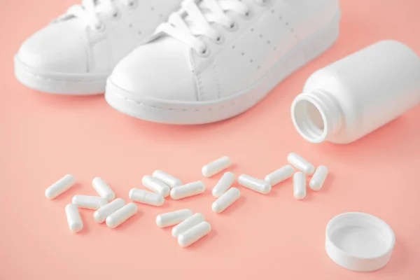 Sneakers and pills. Chondroitin capsules and training shoes. Supportive drugs for the activities and sneakers. Helps support joint health and flexibility. pink background