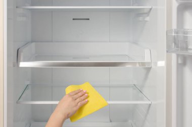 El temizleme buzdolabı. Buzdolabını paçavrayla yıkayan biri. Hizmetçi temiz bir buzdolabının raflarını siler..