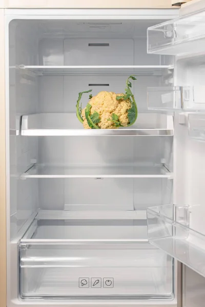 Cauliflower in open empty refrigerator. Weight loss diet concept. Healthy eating.