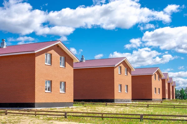 row of new houses against a blue sky with beautiful clouds. Ad layout for a real estate agency. new cottage settlement. real estate sales concept