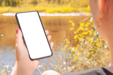 Güz Gölü 'nün orada güneş alan akıllı telefon kullanıyor. Açık havada cep telefonu kullanan bir kadın.