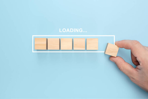 Ручная установка деревянного куба на виртуальную инфографическую загрузочную планку с погрузочной формулировкой. Работа и электронная загрузка прогрессивной концепции. голубой фон
