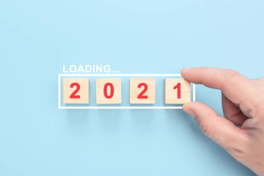 2021 yılı mavi arka planda tahta küplere yüklemek. Elle odun küpünü ilerleme çubuğuna koymak. 2021 yılını insan eliyle dolduruyorum.