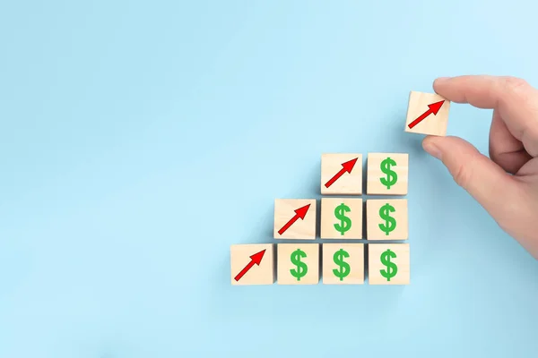 concept of revenue growth. growth on stacked wooden cubes on blue background. Financial or business growth concept. arrows and dollar icons on wooden cubes. copyspace