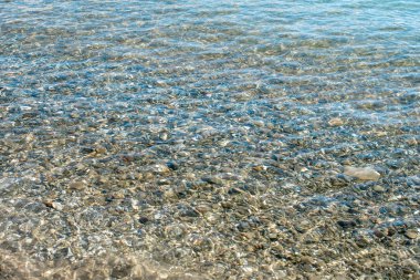 Temiz su ve taşlar. Açık deniz suyunun altında renkli çakıl taşları. Denizin sığ sularında şeffaf su. Denizde temiz su. Temiz deniz sularıyla doğa konsepti.
