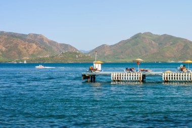 Marmaris Türkiye 'nin deniz manzarası. İnsanlar rıhtımın kamusal alanlarında deniz kenarında güneşlenip banyo yapıyorlar. tatil kavramı