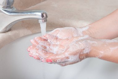 Ellerimi sabunla yıkıyorum. Viral enfeksiyonu önlemek için ellerini banyoda yıkayan bir kadın. Koronavirüs salgını sırasında sabun ve akan suyla yıkanmayı öneriyor. Kavram