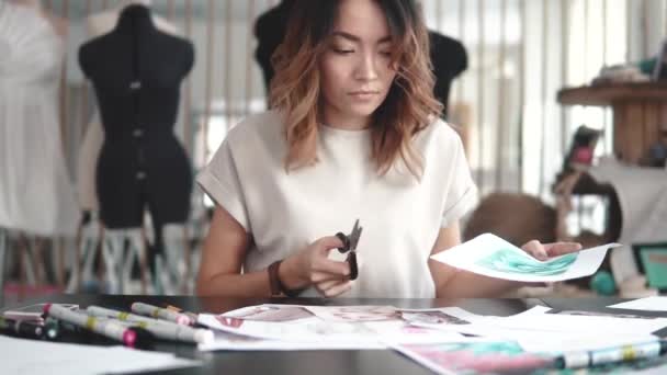 Diseñador de moda hace un collage de dibujos. ropa de diseñador chica hace bocetos en papel. mujer joven que trabaja en un estudio de costura — Vídeo de stock