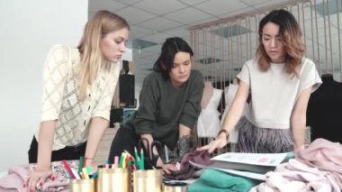 iş kadınları yaratıcı çalışma başlattık. moda tasarımcıları onların küçük stüdyoda çalışmak. seamstresses kumaş giyim yeni bir koleksiyon için seçin
