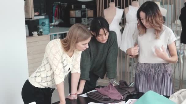 Деловые женщины занимаются творческой работой. Дизайнеры моды работают в своей маленькой студии. швеи выбирают ткань для новой коллекции одежды — стоковое видео