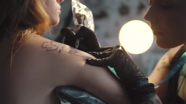 Dibujar un tatuaje en el hombro de cerca. maestro tatuaje hace un rotativo tatuaje ametralladora — Vídeos de Stock