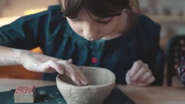 Çocuk bir tabak kil yapıyor. çanak çömlek derste. küçük kız desen bir kil damgası yapar.