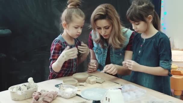 Mutter und zwei Töchter in einem Kreativkurs in der Töpferwerkstatt. Kinder formen Formen aus Ton — Stockvideo