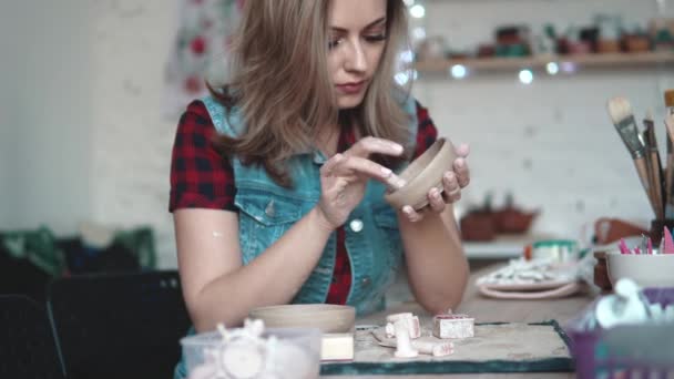 Jonge vrouw wordt een plaat van klei gemaakt in het atelier. meisje met een vorm van klei in haar handen. de creatieve hobby — Stockvideo