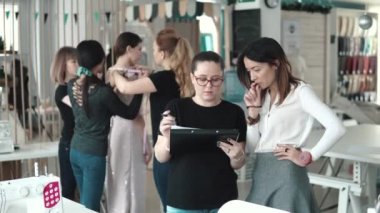 moda tasarımcıları bir Grup modeli elbise tarzı dene. Terziler atelier içinde çalışmak. Tasarımcı ve Yardımcısı elbise kroki kağıt üzerinde arıyoruz