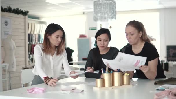 Eine Gruppe von Modedesignern diskutiert Kleidungsskizzen und wählt einen Stoff für die Schneiderei aus. Schneiderinnen im Atelier — Stockvideo
