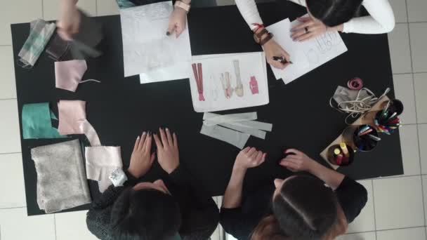 Un grupo de diseñadores de moda discutir bocetos de ropa y elegir un tejido para la sastrería. modistas en el taller. vista superior — Vídeo de stock