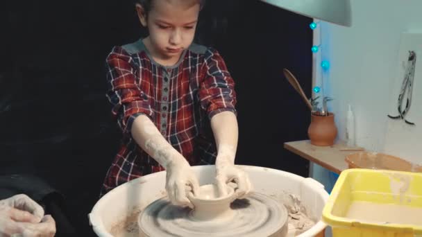 Σοβαρή κοριτσάκι που συγκεντρώνεται στην παραγωγή ένα πήλινα σκεύη στον ένα τροχό αγγειοπλαστικής — Αρχείο Βίντεο
