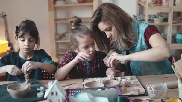 Mother and daughter enthusiastically molded from clay in the pottery. — Stock Video