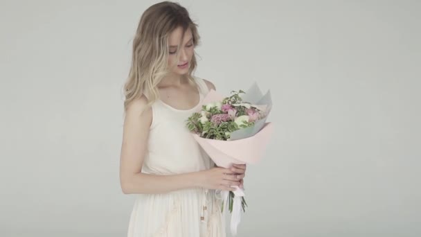 Tierno retrato de una hermosa chica en un vestido ligero con un ramo de flores. cámara lenta — Vídeo de stock