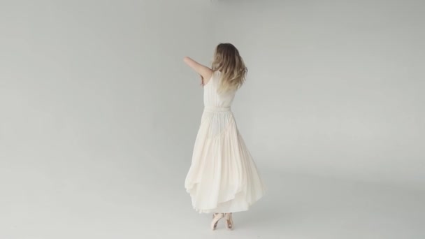 Młodej baletnicy uśmiecha się i elegancko tańczy na palcach w trzepotanie jasną suknię i pointe. zwolnionym tempie — Wideo stockowe