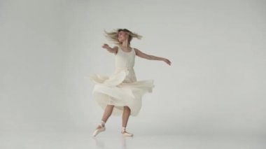 Balerin dans tiptoes pointe Ayakkabı üzerinde dönüyor. balet elbise çırpınan bir ışık. genç çekici kız beyaz bir arka plan üzerinde dans ediyor