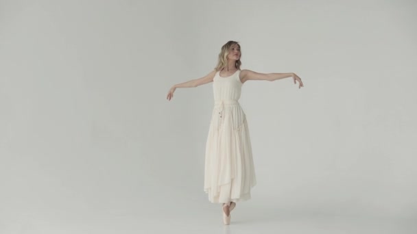 Uma bailarina em um vestido longo e leve e sapatos pontiagudos está dançando balé clássico . — Vídeo de Stock