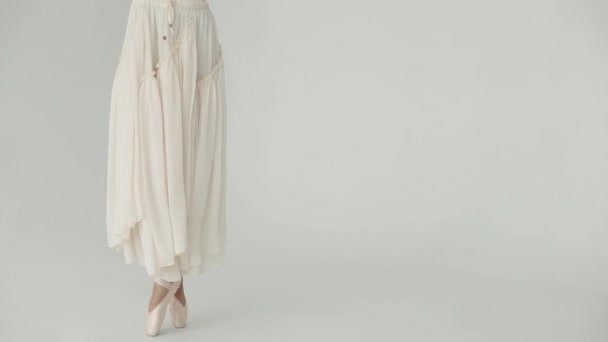 Aantrekkelijk meisje is in een witte jurk dansen op een lichte achtergrond. — Stockvideo