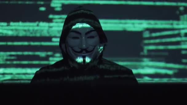 Hacker in het masker hacks het programma. de digitale afpersing krijgt toegang tot de informatie van andere volkeren. de aanval van het virus van de computer. binaire codes projecties en animatie in de achtergrond — Stockvideo