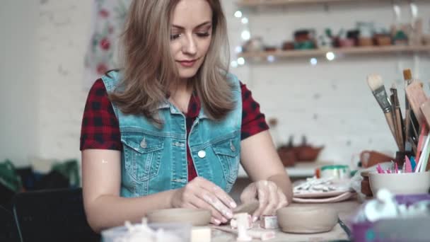 Attraktive junge kaukasische Frau verbringt Zeit hinter einem kreativen Hobby. das Mädchen formt begeistert einen Teller aus Ton in der Werkstatt — Stockvideo