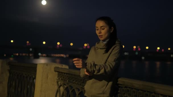 Menina de esportes descansa depois de correr na cidade da noite. monitor de frequência cardíaca atleta em relógios inteligentes e treinamento contínuo . — Vídeo de Stock