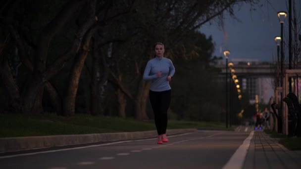 Mladá dívka jogging po opuštěné nábřeží v pozdních večerních hodinách. krásné sportovkyně cvičení venku. Zpomalený pohyb — Stock video