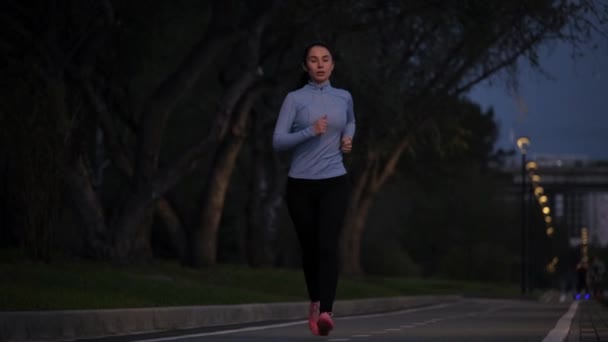 年轻的运动女孩深夜在公园里慢跑。慢动作 — 图库视频影像