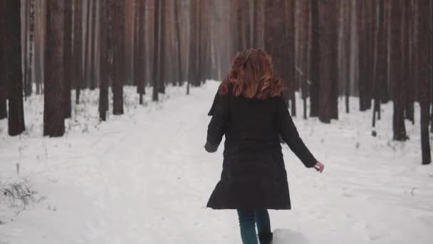 Портрет рыжеволосой девушки с эльфийской внешностью в зимнем лесу. Девушка бежит через зимний лес и смотрит вокруг. замедленное движение — стоковое видео