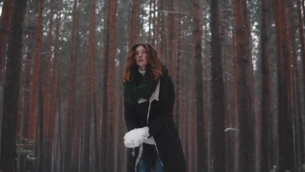De roodharige meisje sneeuw omhoog gooit en lacht. sneeuwvlokken op haar. Slow motion — Stockvideo