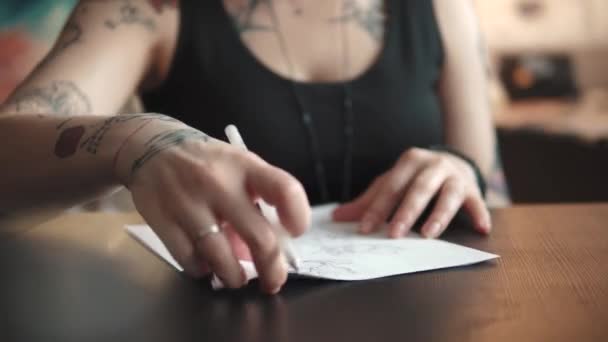 Tattoo kunstenaar maakt een schets van de tatoeage op papier in een home Studio — Stockvideo