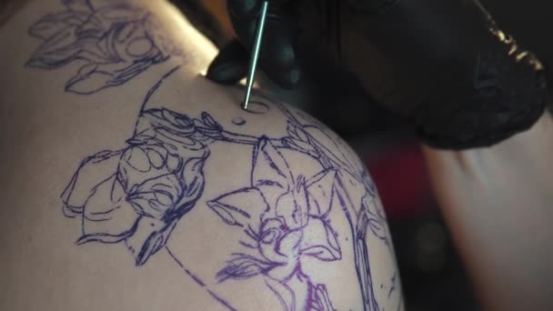 drawing a tattoo on the shoulder close up. master tattoo makes a rotary tattoo machine gun