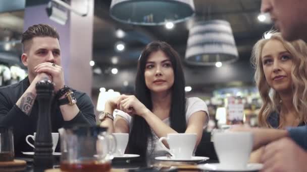 Amigos se ríen y se divierten sentados en una mesa en un restaurante. Una compañía de amigos pasa tiempo juntos y disfruta socializando . — Vídeos de Stock