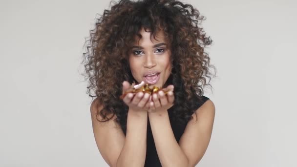 Flicka blåser konfetti och leende. Porträtt av en charmig spansktalande curly flicka flygande paljetter och konfetti. konceptet för semester, kul, fira. slowmotion — Stockvideo