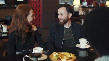 Genç bir adam ve bir kız bir kafe ya da restoran bir masada oturan ve eğlenceli konuşuyor