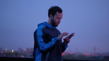 Genç bir adam bir cep telefonu günbatımında kullanır..